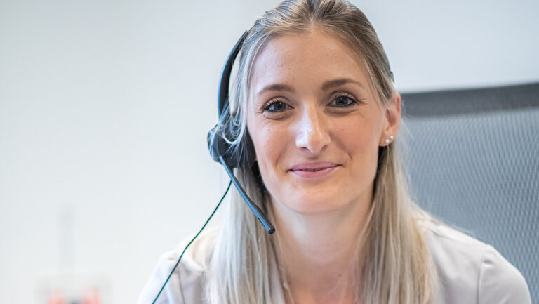 Frau mit Headset lächelt in Kamera