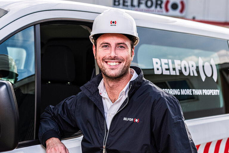 Man in front of a BELFOR Car