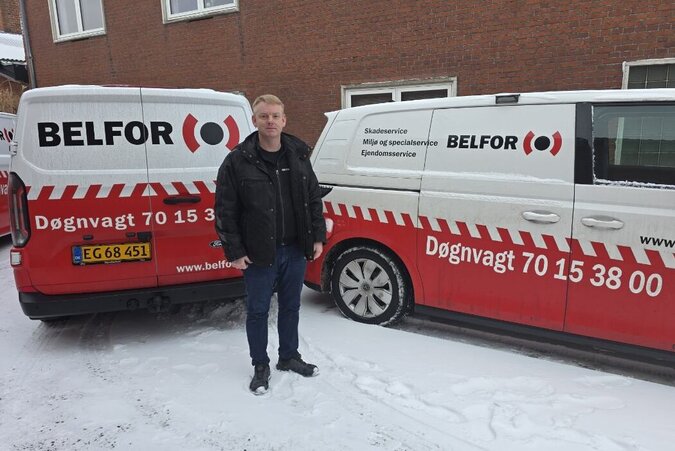 BELFOR-medarbejder i sort jakke står foran en række udrykningskøretøjer.