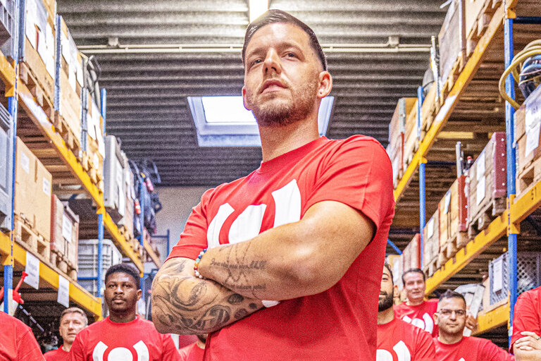 Gruppe von BELFOR Kollegen in Arbeitskleidung zeigt Teamgeist in einer Halle.